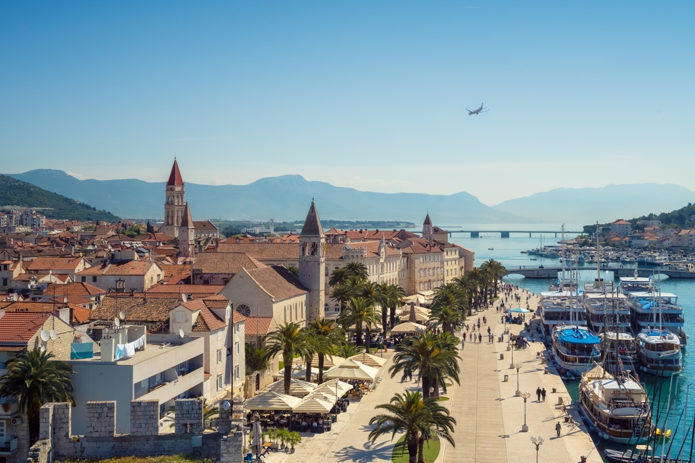 Ez a kép Trogir történelmi óvárosát és a tengerparti sétányát (Trogirska Riva) ábrázolja Horvátországban. 