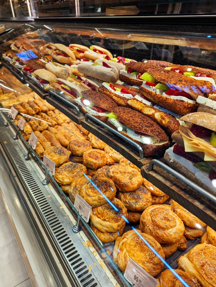 A képen egy pult látható, amely különféle hagyományos török pékárukat és szendvicseket kínál. 